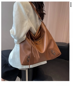 Detail view of large brown leather tote bag with vintage rivets and tassel zippers