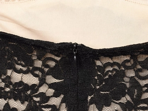 Close-up of black floral lace fabric with beige lining and invisible zipper on dress back
