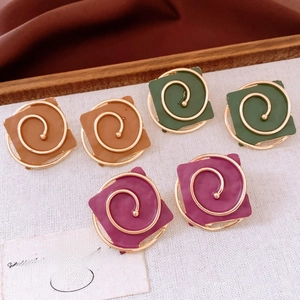 Detail of square retro earrings in green, brown and burgundy with gold spiral accents