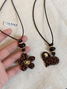 Close-up of leopard print heart and flower resin pendants with rhinestones on wax cord