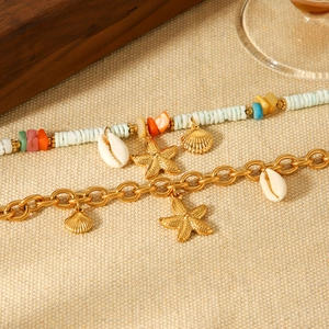 Gold 18k stainless steel starfish and seashell bracelet set on beige textured background