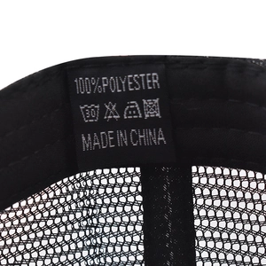 Detail of internal fabric label on black mesh baseball cap showing 100% polyester material