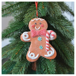 Close-up of gingerbread man ornament with candy cane details on a green Christmas tree