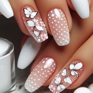 Macro detail of French style press-on nails with butterfly, dot, and floral rhinestones