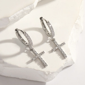 Silver cross hoop earrings with sparkling cubic zirconia on white stone pedestal