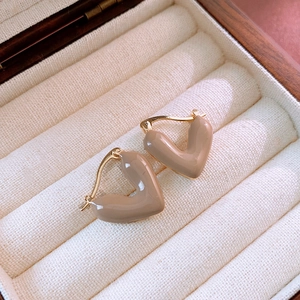 Detail of vintage heart-shaped gold hoop earrings with light brown enamel finish