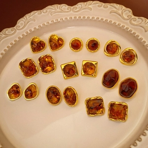 Close-up of assorted amber resin geometric earrings in a vintage ceramic plate