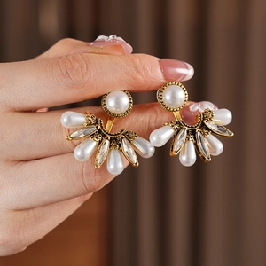 Macro detail of vintage fan-shaped pearl earring featuring gold alloy and sparkling crystals