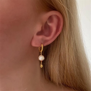Detail of s925 silver twist hoop earrings with pearl and sunburst gold charm