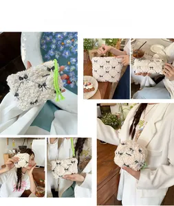 Detailed macro view of cream faux shearling makeup bag with black bow embroidery