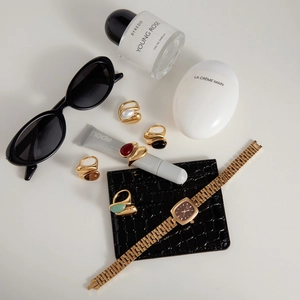 Flatlay von goldenen Edelstahlringen mit Natursteinen und einer Vintage-Uhr