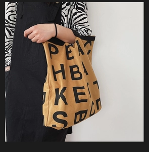 Detailed view of khaki canvas tote bag with black letter print on zebra pattern shirt