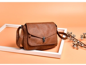 Detailed view of a vintage brown leather shoulder bag with a metal rotating clasp