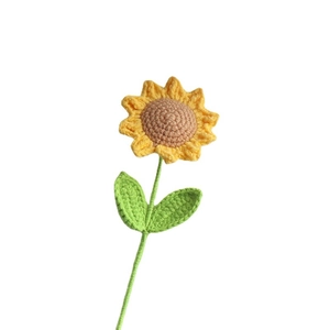 Handmade crochet sunflower with yellow petals and green leaves on white background