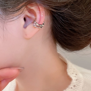 Close-up of a silver-tone wavy ear cuff with a pink gemstone on a model's ear
