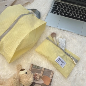 Macro detail of yellow checkered waterproof travel organizer bags on white plush carpet