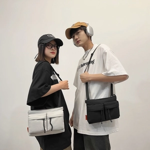 Unisex nylon messenger bag with double front pockets available in black and white colors