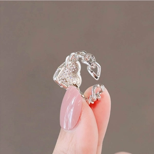 Close-up of a silver heart ring with pavé crystals and a chain-link adjustable band