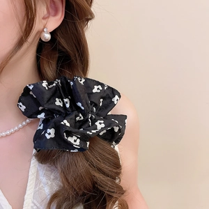 Detail of floral fabric scrunchie with white patterns on model's long wavy brown hair