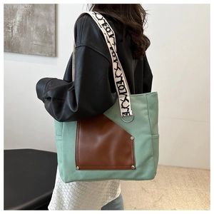 Detail of mint green canvas tote with brown leather pocket and patterned wide strap