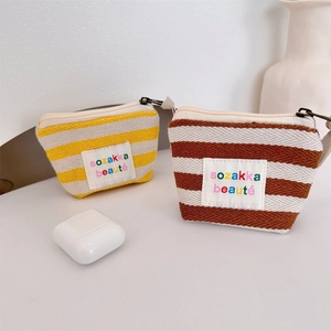Close-up of yellow and brown striped fabric pouches with metal zipper and brand patch