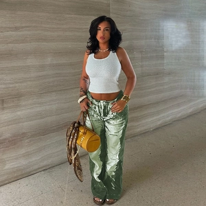 Full-body shot of a chic woman in white tank top and green printed wide-leg trousers