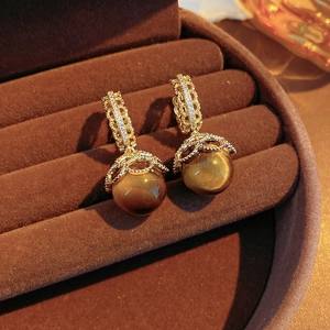 Macro detail of gold-plated tiger eye earrings with cubic zirconia in a velvet box
