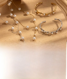 Detailed view of titanium steel pearl necklace and textured gold wave bracelets