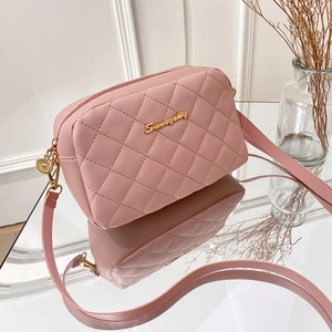 Pink quilted crossbody camera bag with gold hardware and logo on glass table