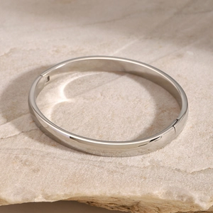 Close-up of a polished stainless steel flat oval bangle with a functional clasp closure