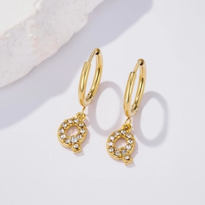 Detailed view of gold plated letter Q earring with sparkling zircons on white rock