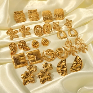 Détail de diverses boucles d'oreilles géométriques dorées sur du tissu satiné blanc