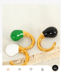 Detailed macro view of three C-shaped gold earrings with green, white, and black enamel decor