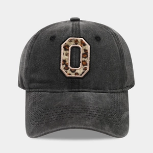 Macro detail of leopard print letter O embroidery on washed black cotton baseball cap