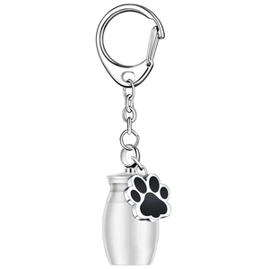 Detail of silver pet urn keychain featuring a black paw print charm and metal cylinder