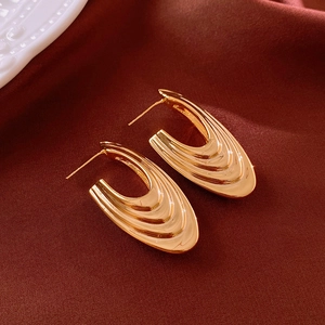 Macro shot of gold-plated U-shaped earrings with unique folded texture on satin