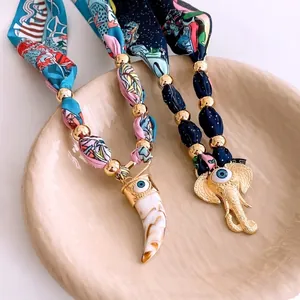 Retro silk scarf necklace with ivory and elephant charms in a ceramic tray