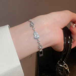 Detail shot of a silver bracelet featuring delicate pearls and a gourd-shaped zircon charm