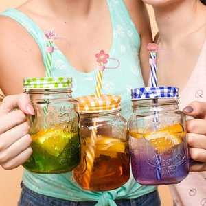Pink silicone floral straw covers in daisy and cherry blossom shapes on mason jars