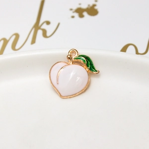 Macro shot of peach-shaped alloy pendant with pink enamel and gold-plated details
