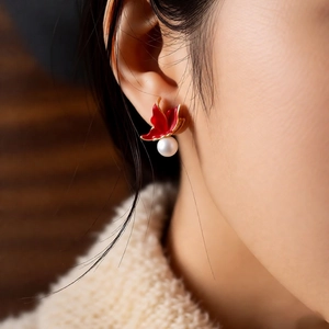 Gros plan de boucles d'oreilles fleur rouge et perle avec placage en or