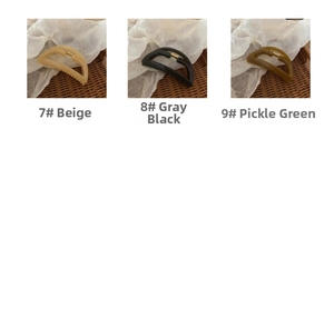 Minimalist large hair claws in cream, grey-black, and pickle green on textured fabric