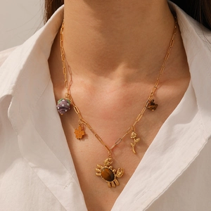 Gold-plated paperclip necklace with maple leaf, rose, and stone crab pendants on a model