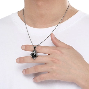 Macro view of vintage cross pendant with black zircon on punk steel chain on model
