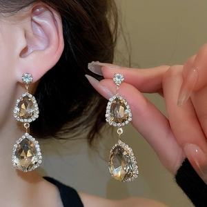 Detail view of pear-shaped champagne stone drop earrings with sparkling diamond halo