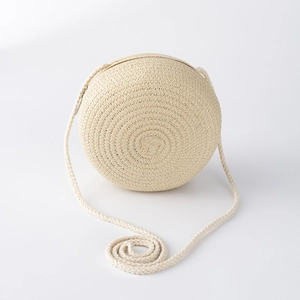 Détail d'un sac à bandoulière rond en paille beige pour filles avec une longue lanière