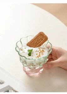 Détail d'un bol en verre en forme de pétale avec base rose rempli de yaourt et d'avoine