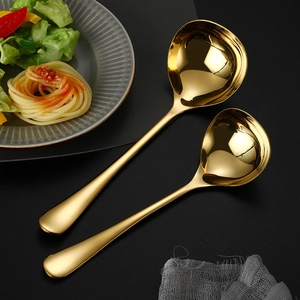 Set of two gold 304 stainless steel soup spoons on a black background with pasta