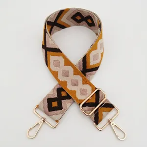 Close-up of diamond pattern jacquard bag strap with golden metal clips and pink brown weaving