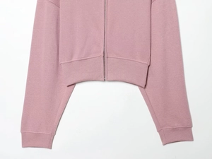 Détail d'un sweat à capuche rose avec fermeture éclair et ourlet côtelé